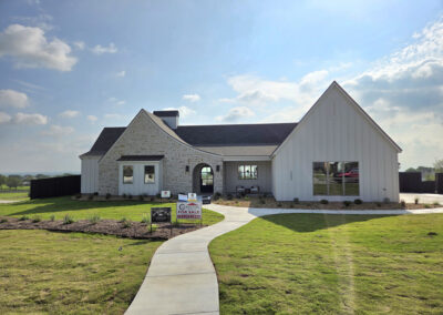 Hill Country-style home with mixed stone and stucco exterior, multiple peaked gables, and detached garage wing