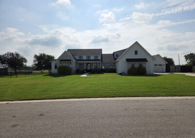 Two-story custom home with stone and stucco exterior and dark roof, set on a freshly landscaped lot