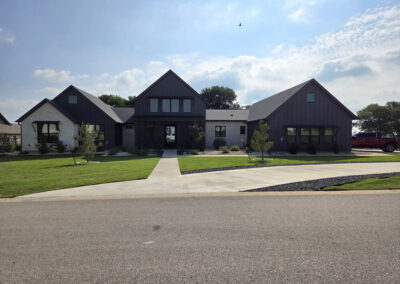 Newly completed two-story home with stone front, two-car garage, and circular driveway in suburban Texas