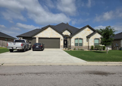 Brick single-story home with covered entry, three-car garage, and pickup truck parked in the driveway
