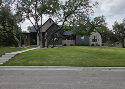 Mature shade trees in front of a custom-built Central Texas home along a residential street