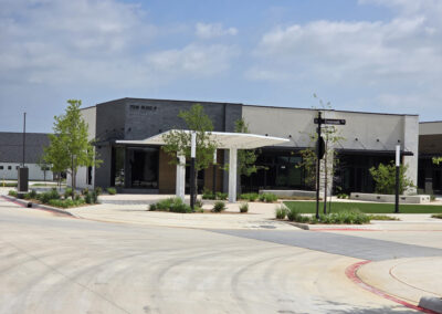 End-cap commercial unit with mixed dark stucco and light stone, metal awnings, and covered walkway