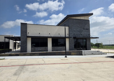 Single-story commercial retail space with dark gray exterior, large storefront windows, and ADA-accessible entry