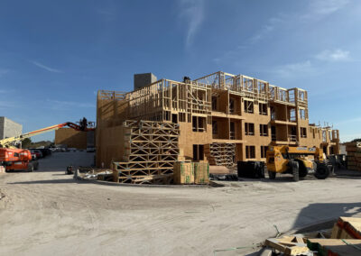 Large mid-rise apartment complex under construction showing extensive wood truss framing across multiple floors