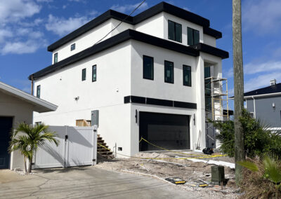 Modern two-story home under construction with white stucco exterior, black trim, and oversized garage