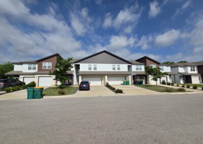 Newly completed townhome development with neutral siding, paired garages, and freshly poured driveways