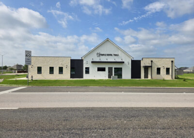 Modern single-story dental office with stucco exterior, dark metal roof, and clean architectural lines