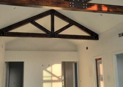 Interior great room with a vaulted ceiling and dark heavy timber scissor truss overhead.
