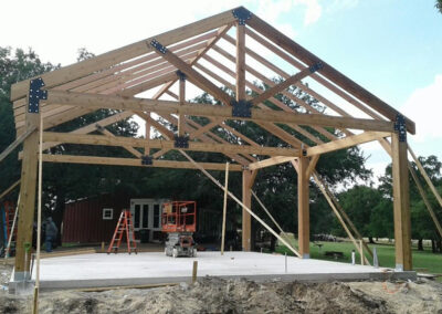 Heavy timber gable frame with king post, freshly erected under an open sky.