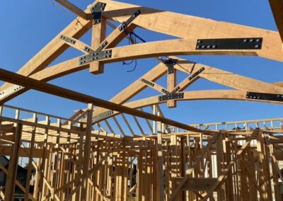 Exposed heavy timber roof framing during construction, angled rafters and braces visible.