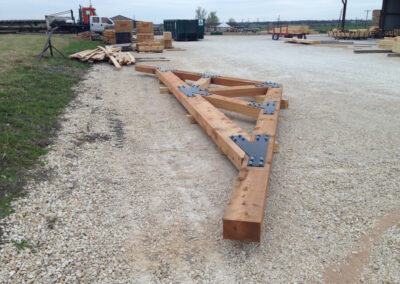 Multiple fabricated trusses laid out on a gravel staging yard before delivery.