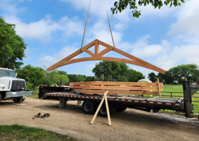 Heavy timber truss assembly staged outdoors against a blue sky.