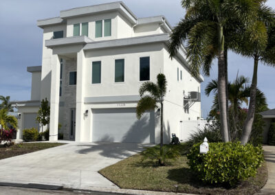 Completed custom two-story coastal home with a side-entry garage and palm landscaping.
