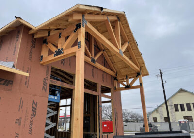 Heavy timber frame under construction at a dental office, exposed raw timber posts and beams with sheathing in progress.